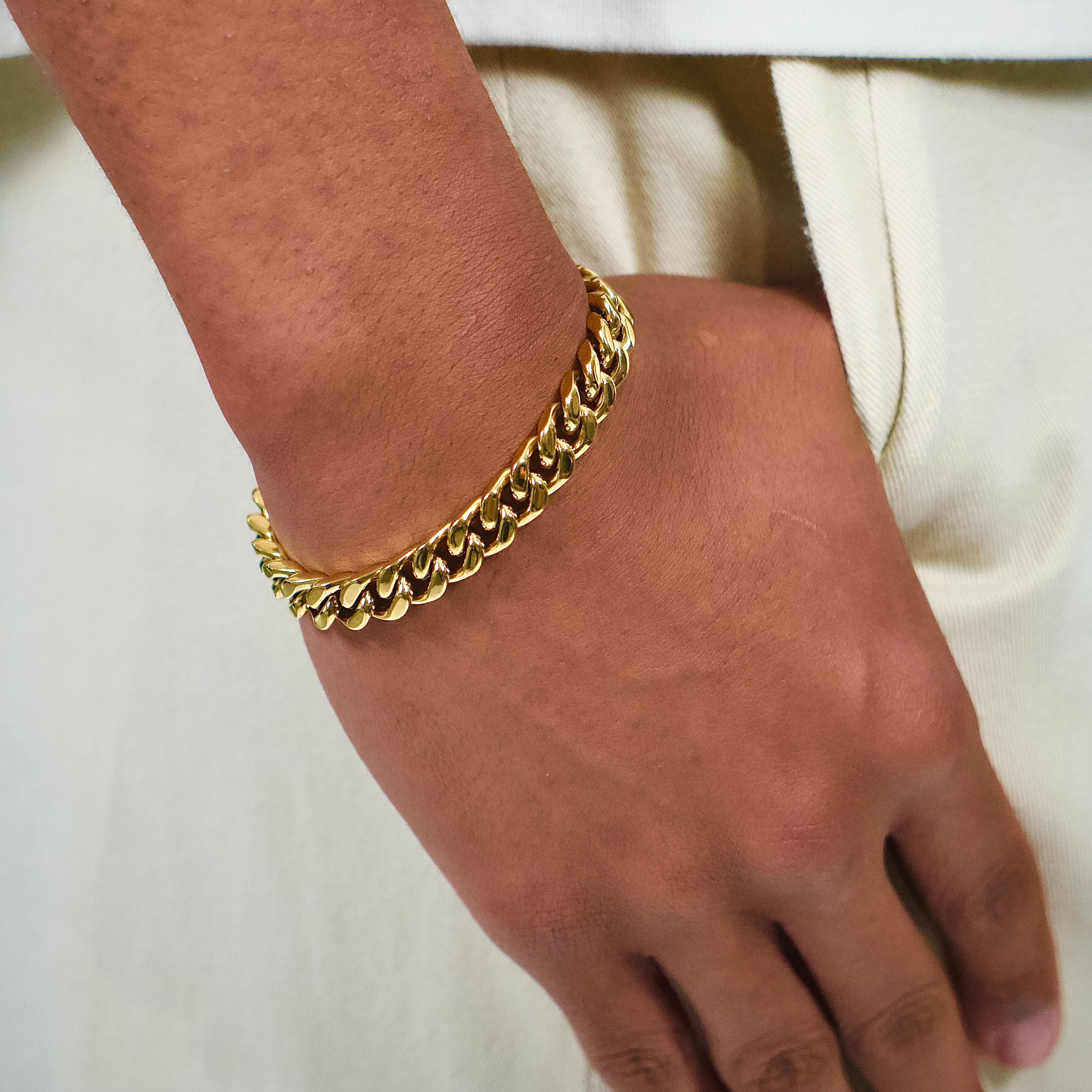 This is a side close up shot of our 10mm yellow gold cuban link bracelet on a models wrist without the box clasp being displayed