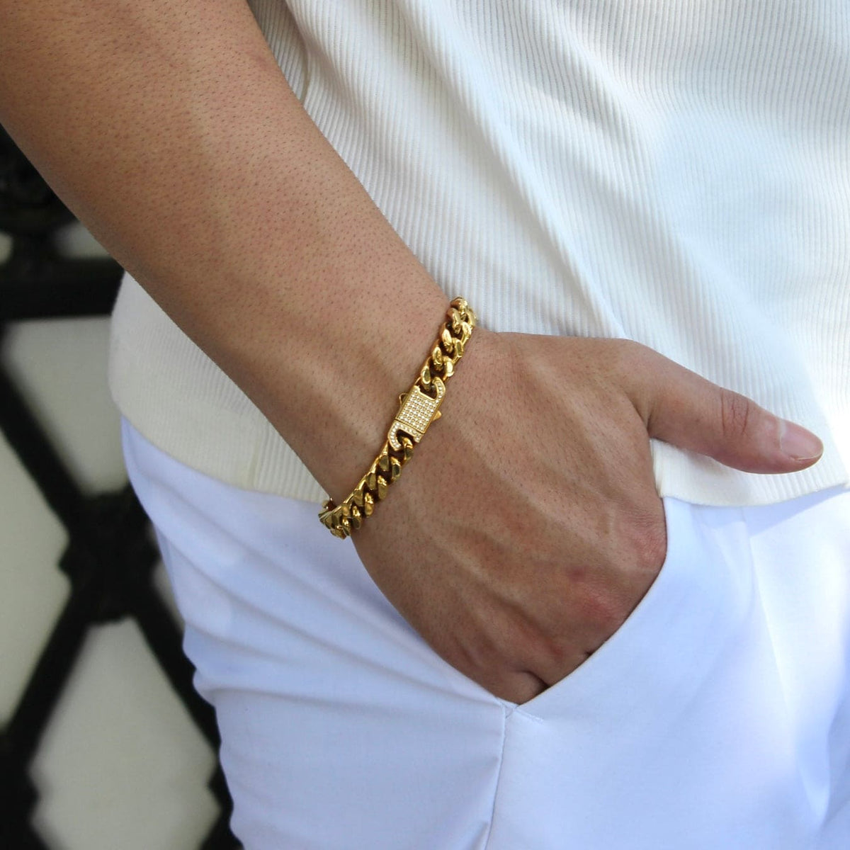 This is a side close up shot of a model wearing our 10mm yellow gold cuban link bracelet with the models hand in his pocket