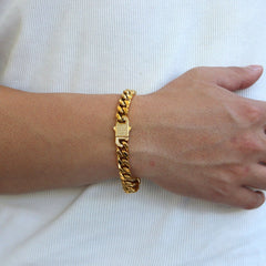 This is a side shot of our 10mm yellow gold cuban link bracelet on a models wrist with the bracelet clasp showing