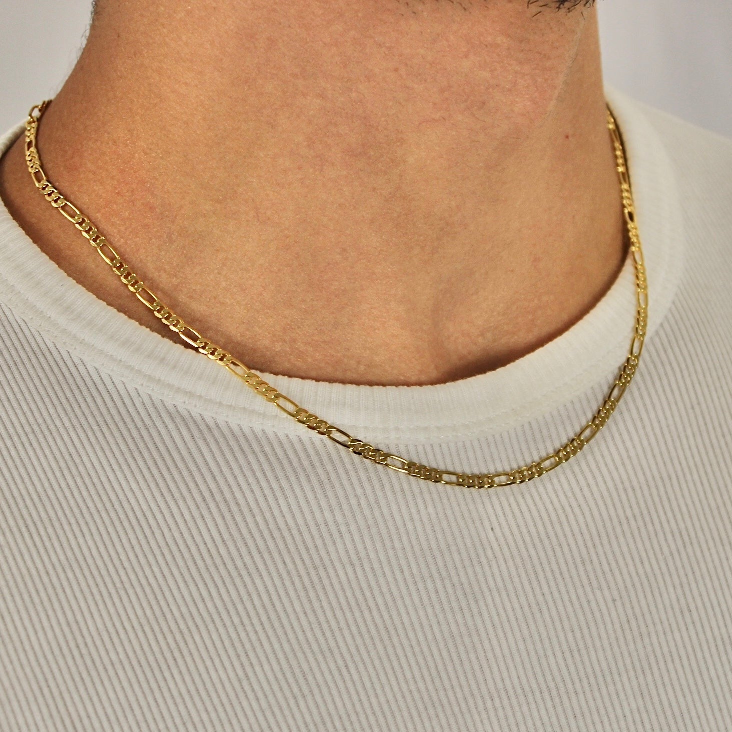 This is a front closeup shot of our 3mm 18k sterling silver figaro chain on a models neck