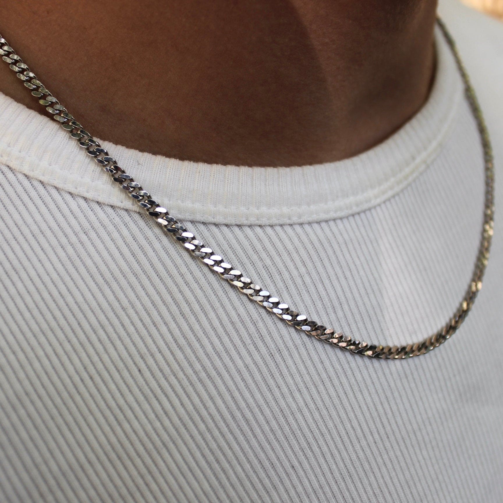 This is an extreme close up shot of our 3mm sterling silver cuban link/curb chain on a models neck taken in public scenery 