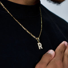 This is a close up shot of our 3mm yellow gold figaro chain in sterling silver with our letter pendant on it