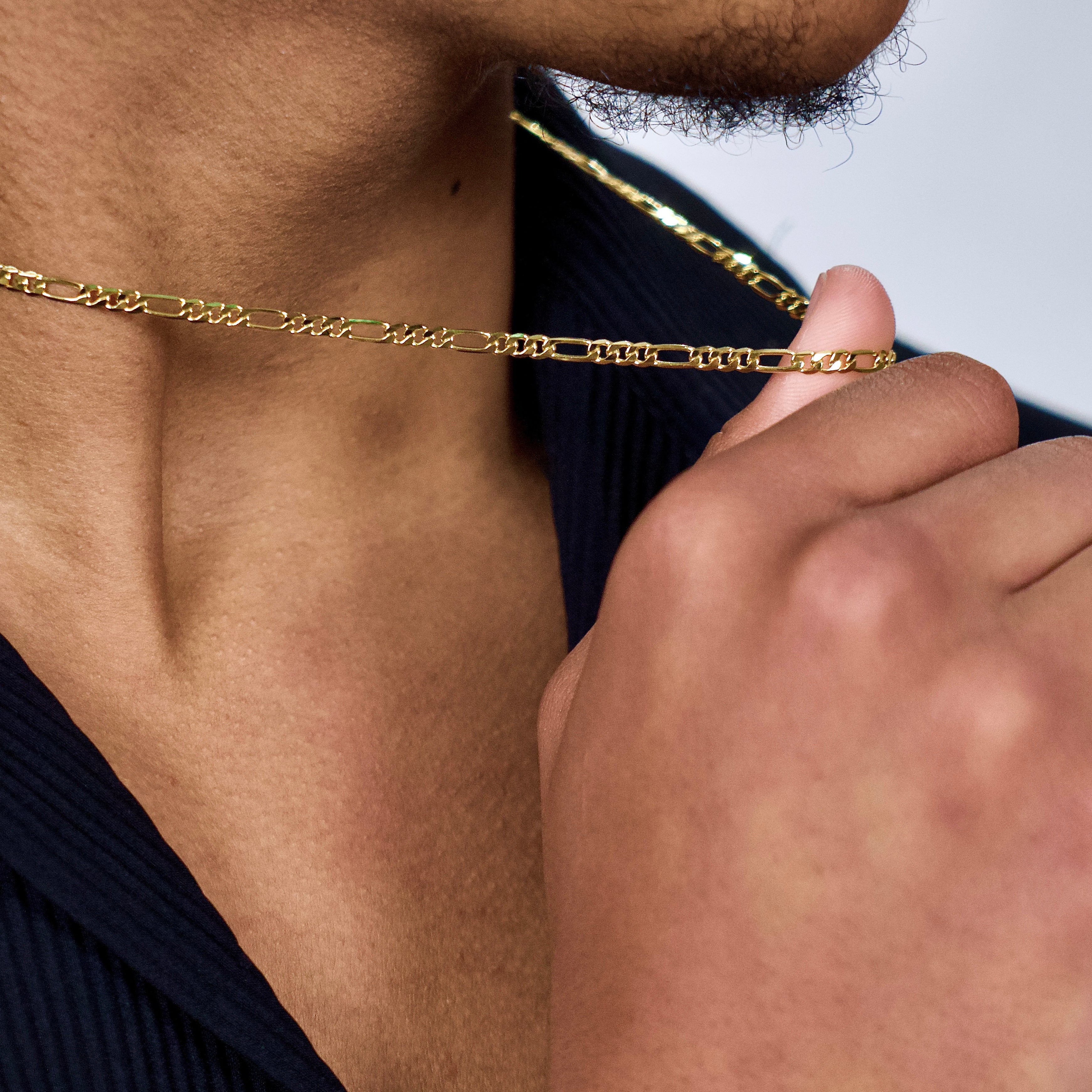 This is an extreme close up shot of our model wearing our 3mm sterling silver yellow gold plated figaro chain 