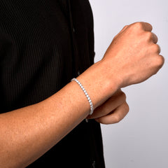 This image is a side shot of a model wearing our 4mm Sterling Silver Round-Cut Tennis Bracelet on the right wrist and is taken on a white backdrop in a studio