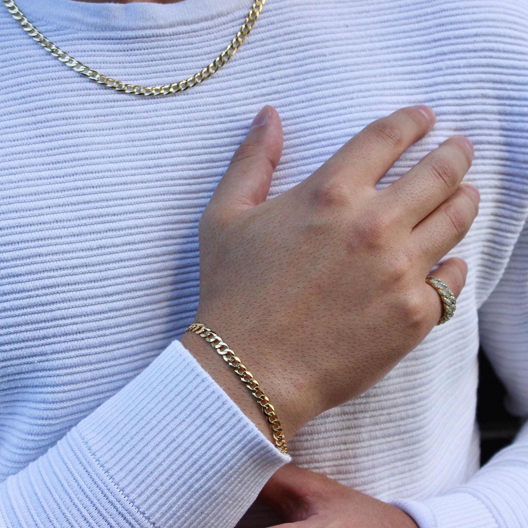 This is a mid shot of our 5mm yellow gold curb bracelet on our models wrist showing how to style the bracelet with a ring