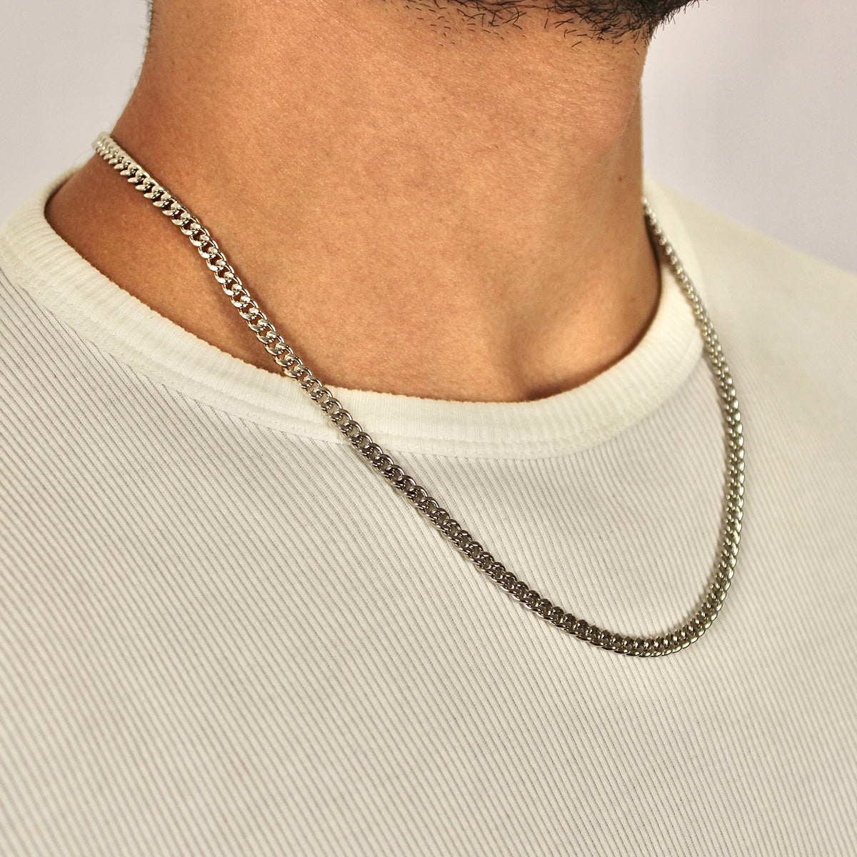 This is a side close up studio shot of a model wearing our 5mm sterling silver cuban link chain necklace on around his neck