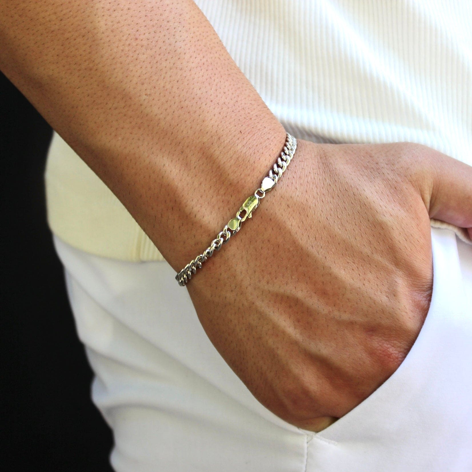 This is a close-up shot of our 5mm sterling silver cuban bracelet on our models wrist with the models hand in there pocket with the clasp being shown