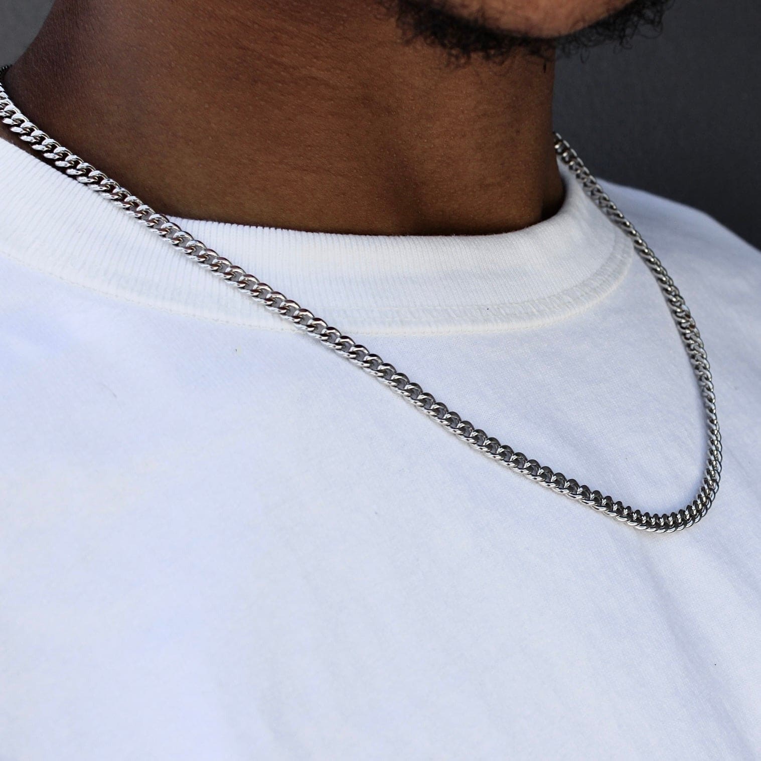 This is a close-up side shot of our 5mm sterling silver rhodium plated cuban link chain on a models neck.