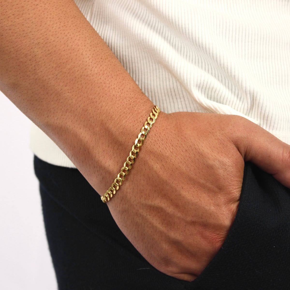 This is a close up shot of our 5mm yellow gold curb bracelet on our models wrist with his hand in his pocket