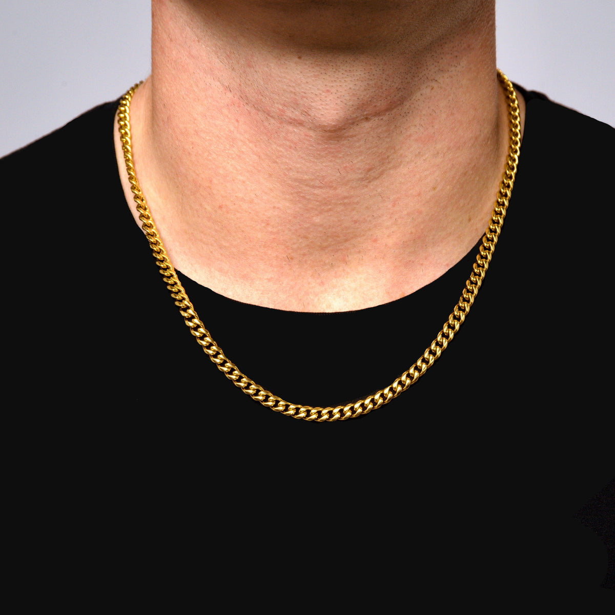 This is a close up shot of our 6mm yellow gold cuban link chain with lobster clasp on models neck.