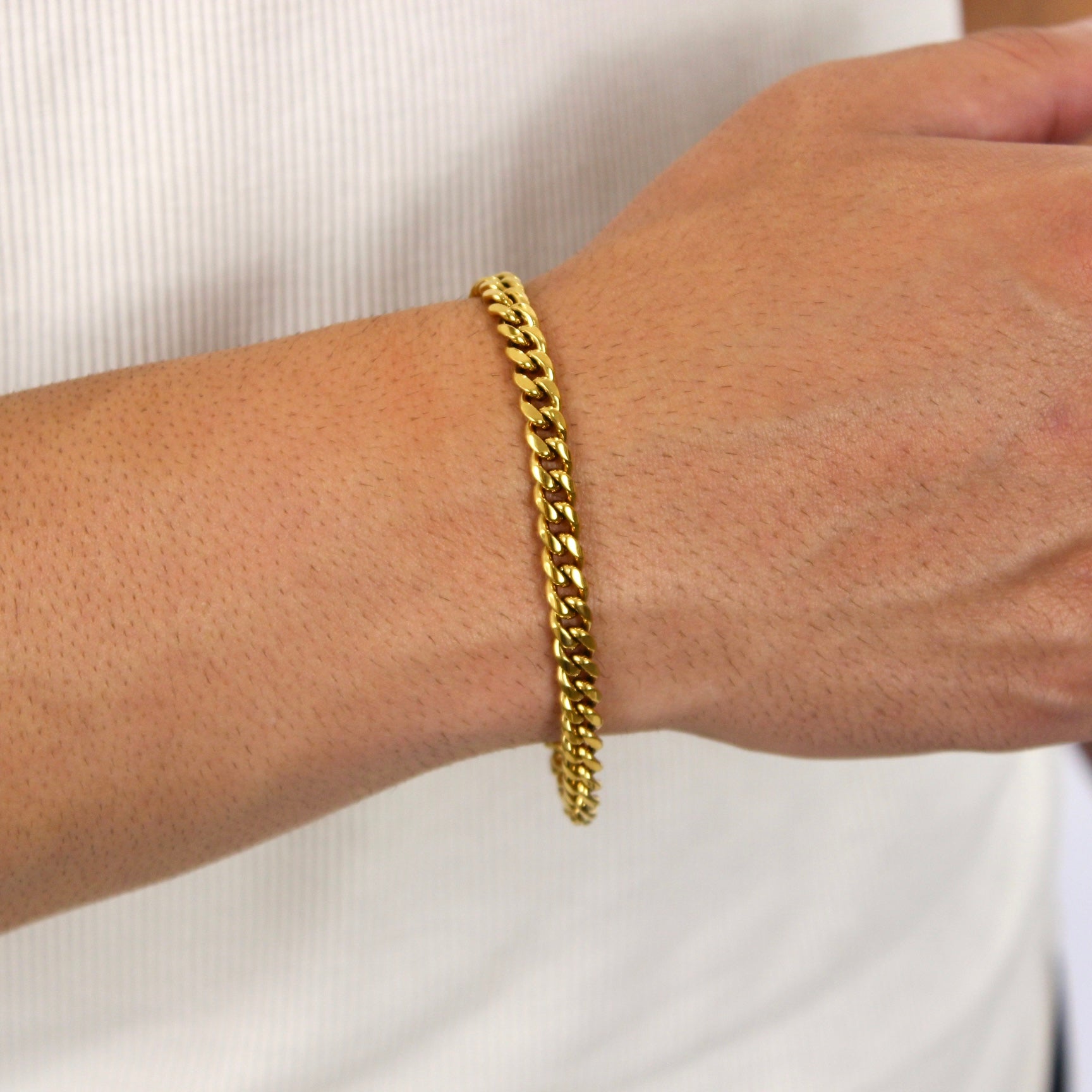 This is an extreme close up shot of our 6mm yellow gold cuban link bracelet on a models wrist