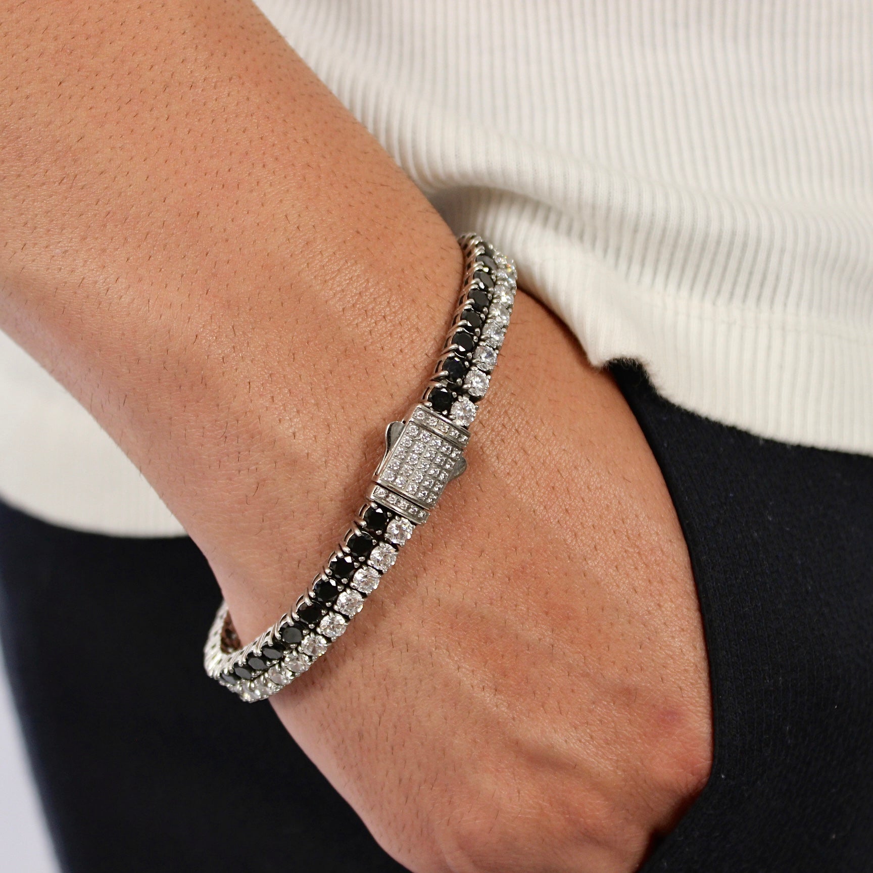 This is a side shot taken in a studio of a models wrist, wearing our 8mm dual white & black tennis bracelet with the clasp being displayed