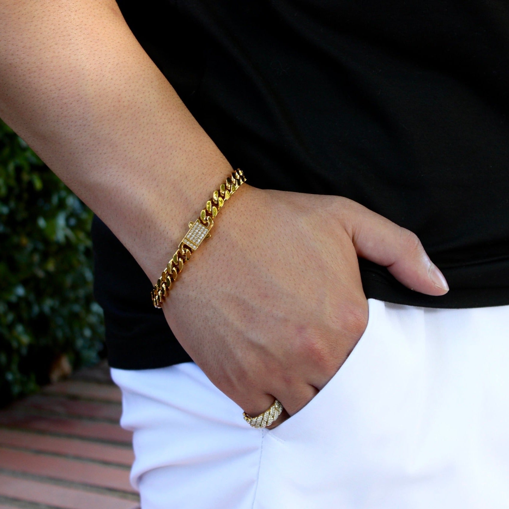 This is a eye level shot of our 8mm yellow gold cuban bracelet with the cubic zirconia clasp being shown, with the models hand in his pocket