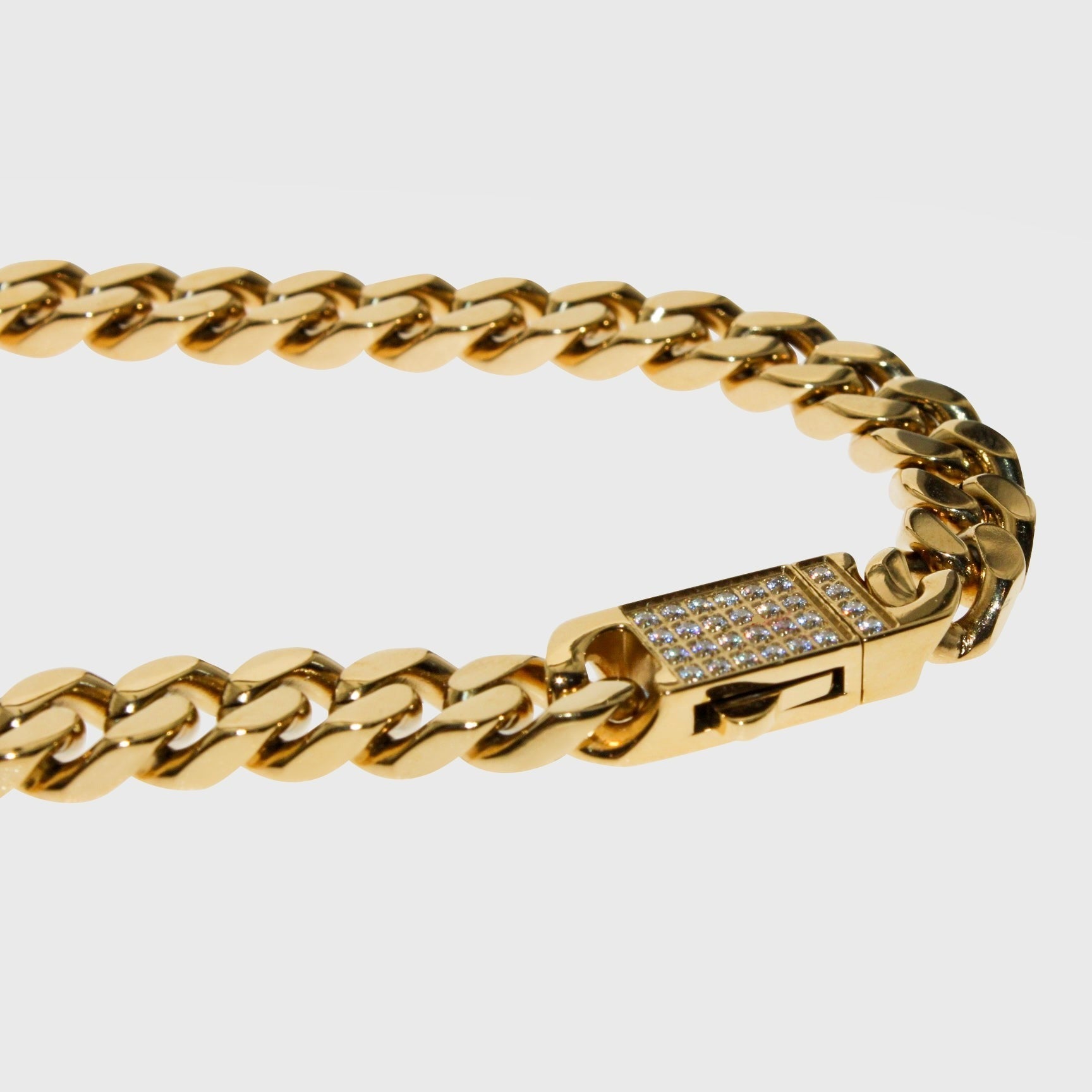 This is a product shot taken in a light box of our 8mm yellow gold cuban link bracelet with our cubic zirconia clasp being shown