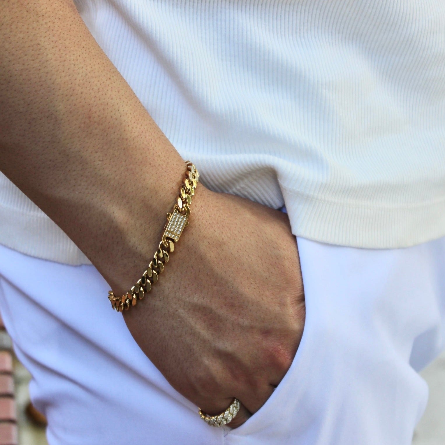 This is Mid shot image of our 8mm yellow gold cuban bracelet on our models wrist with his hand in his pocket.