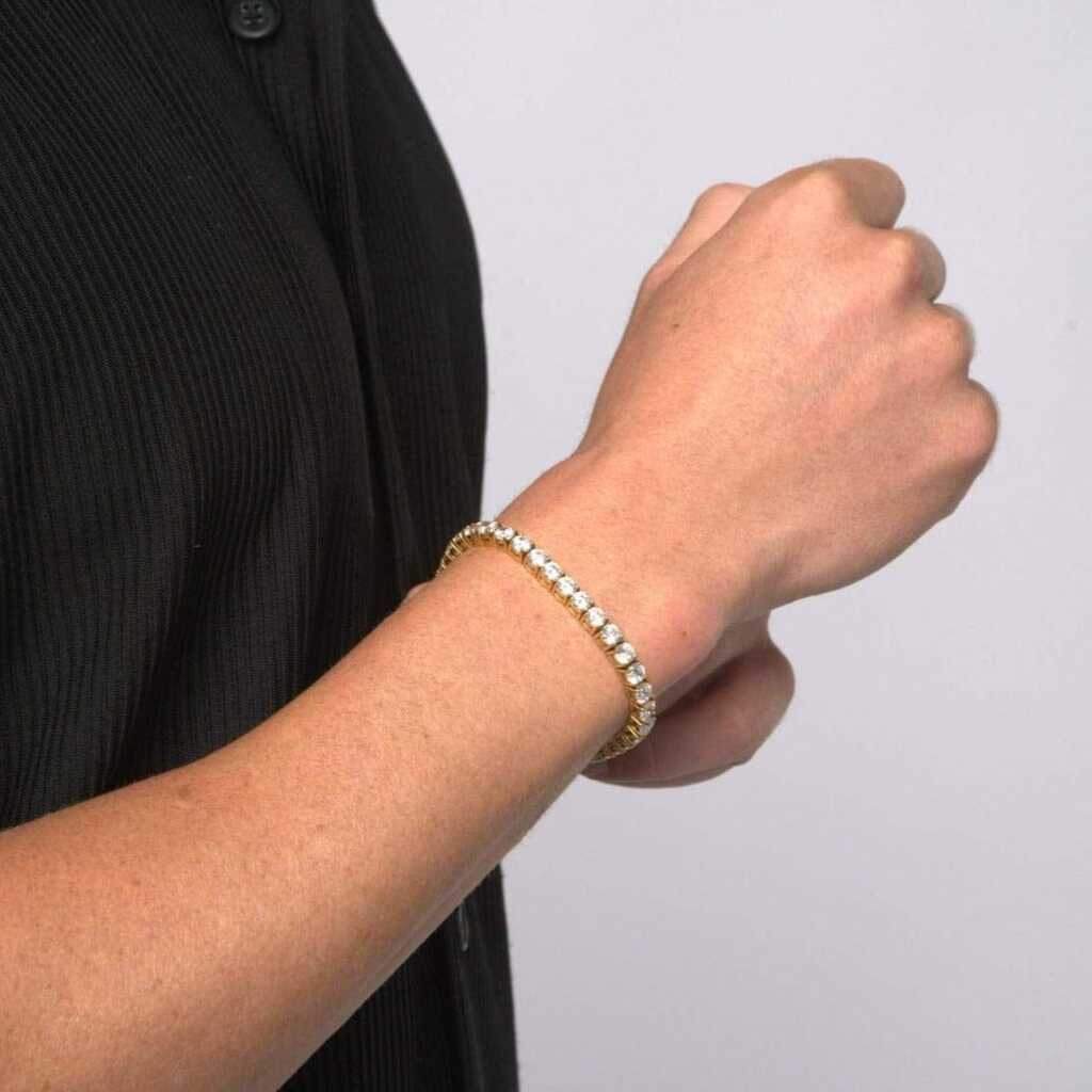 This image is a side shot of a model wearing our 5mm yellow gold tennis bracelet